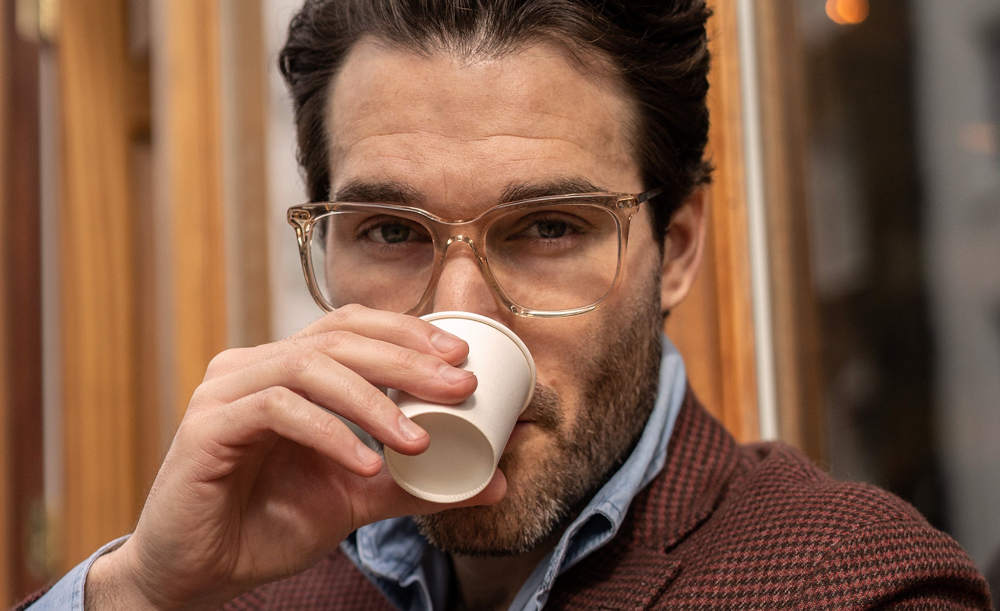 Man sipping espresso from paper cup wearing crystal clear glasses frame