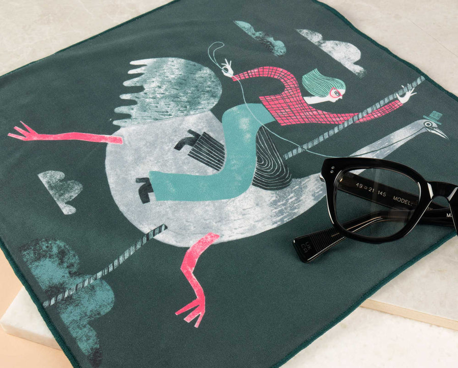 Black spectacle frame lying on top of oversized green coloured lens cleaning cloth